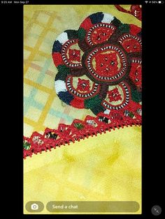 an applique on the side of a yellow blanket with red and green designs