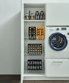 a washer and dryer in a white cabinet with shelves filled with beer bottles