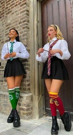 two young women dressed in school uniforms standing next to each other on the side of a building