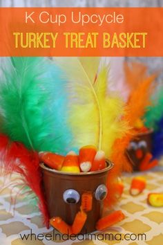 a cup filled with candy and feathers sitting on top of a table next to a turkey treat basket