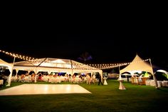 an outdoor wedding reception at night with white tents and string lights strung over the dance floor