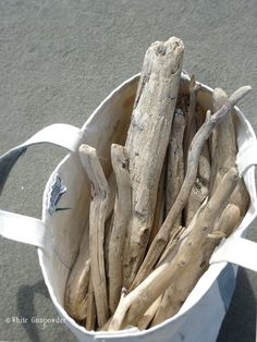 a white bucket filled with driftwood sticks