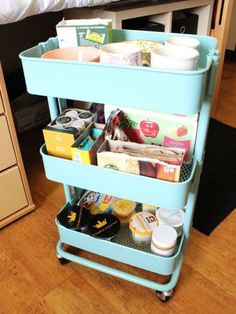 a blue cart filled with lots of food on top of a hard wood floor next to a bed