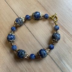 This 7 inch bracelet features sodalite beads, goldtone bead caps, and goldtone beads, with a goldtone toggle clasp. This bracelet weighs .48 ounces. Sodalite properties: * unites logic and intuition * eliminates mental confusion * encourages rational thought, objectivity, trust,  * brings intuitive perception * aids with verbalization of feelings * calms the mind * brings emotional balance * aids group work * balances metabolism * benefits cleansing organs * boosts immune system Brass Beaded Bracelets With Round Beads, Blue Kyanite Round Bead Jewelry, Brass Bracelets With Round Gold Beads, Gold Hand-strung Czech Glass Bracelets, Hand-strung Gold Jewelry With Czech Glass, Gold Czech Glass Hand-strung Bracelet, Hand-strung Gold Czech Glass Jewelry, Gold Czech Glass Jewelry, Hand-strung, Adjustable Sodalite Gemstone Beaded Bracelets