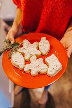 a woman is holding a plate with cookies on it and sprig of rosemary