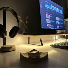 a computer desk with headphones on it and a monitor in the backround