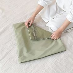 a woman is sitting on the floor with her hand in an empty bag that has been folded over