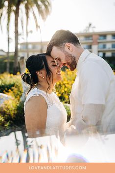 a bride and groom standing next to each other in front of palm trees at sunset