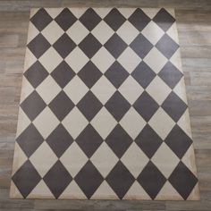 a black and white checkered area rug on the floor with wood floors in the background