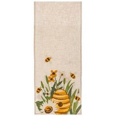 a kitchen towel with bees and flowers on the front, hanging from a white wall