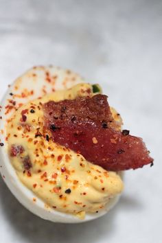 deviled eggs with bacon on top in a white bowl and text overlay reads candied bacon jalapenos deviled eggs