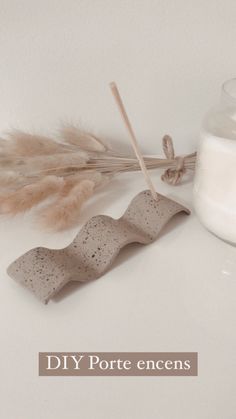 a candle and some feathers on a white surface with the words diy porte enceens