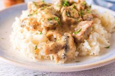 a white plate topped with rice and meat covered in gravy on top of a table