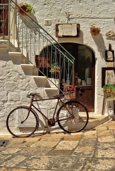 a bicycle parked in front of a white building with steps leading up to the door