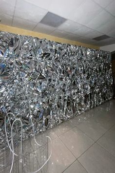 a large pile of silver foil sitting on top of a floor next to a wall