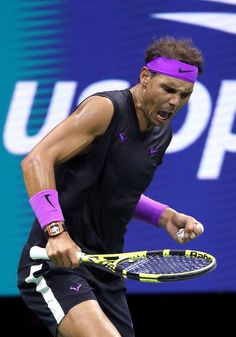 a man holding a tennis racquet in his right hand and yelling at the ball