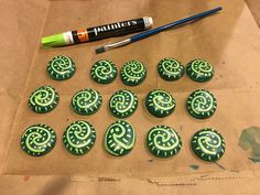 green and white decorated cookies sitting on top of a brown paper bag next to a paintbrush