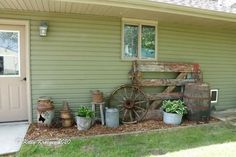 an old wooden wagon sitting on the side of a house next to potted plants