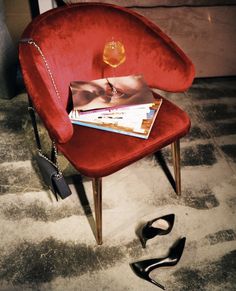 a red chair sitting on top of a carpet next to a pair of black shoes