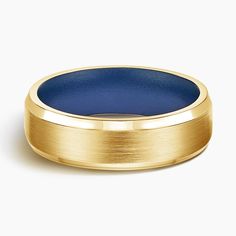 a gold wedding ring with blue inlays on the inside and outside, against a white background