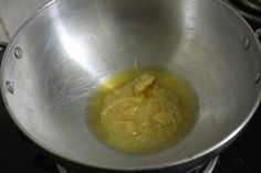 a metal bowl filled with yellow liquid on top of a stove