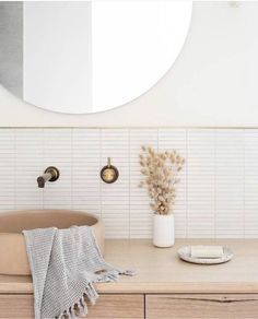 a bathroom with a round mirror above the sink