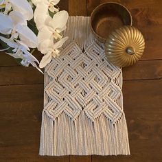 a table with white flowers and a gold vase on top of it next to a crocheted doily