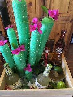 a wooden box filled with bottles and fake cactus plants in the shape of vases