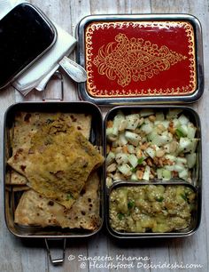 three metal containers filled with food on top of a wooden table