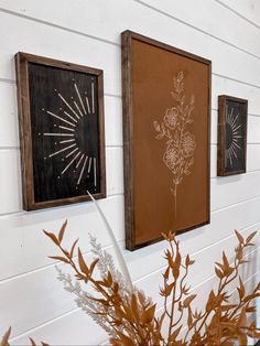 three framed pictures hang on the wall next to a potted plant