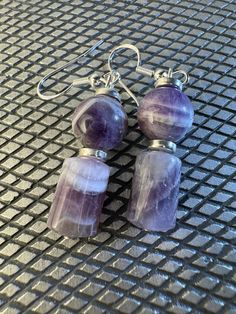 These earrings feature Chevron Amethyst barrel and round beads with Silver Spacer Beads. The ear loops are 0.925 sterling silver. Silver Gemstone Bead Round Earrings, Sterling Silver Gemstone Bead Earrings, Silver Round Gemstone Bead Earrings, Silver Gemstone Beads Earrings, Sterling Silver Earrings With Round Gemstone Beads, Silver Earrings With Gemstone Round Beads, Silver Earrings With Gemstone Beads, Round Amethyst Earrings With Natural Stones, Purple Gemstone Bead Dangle Earrings