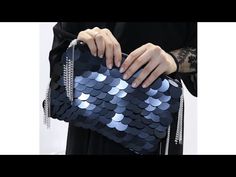 a woman is holding a blue sequin clutch bag