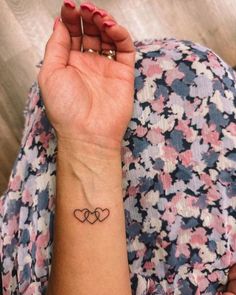 a woman's wrist tattoo with two hearts on the left side of her arm