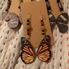 a pair of butterfly shaped earrings with beads on them sitting on top of a bed