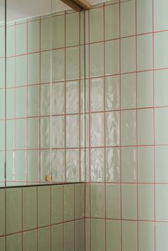 a white tiled bathroom with red lines on the shower wall and tile around the bathtub