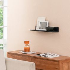 a living room with a table and chair next to a wall mounted shelf on the wall