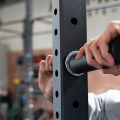 a man is using a pull up bar in a gym with his hands on the bars