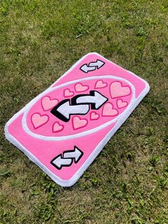 a pink towel with hearts and arrows on it laying in the grass next to a pair of scissors