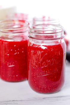 three jars filled with red liquid sitting on top of a table