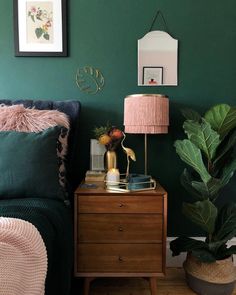 a bedroom with green walls and two pictures on the wall above the bed, next to a nightstand with a lamp