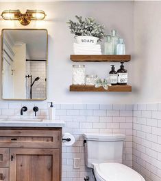 a white toilet sitting next to a wooden sink vanity in a bathroom under a mirror