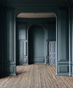 an empty room with blue walls and carpeted flooring in front of two doorways