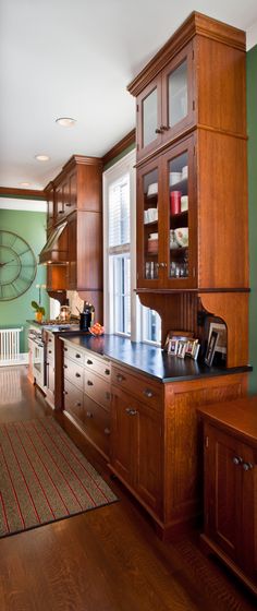 a kitchen with green walls and wooden cabinets in the center, along with an area rug on the floor