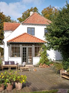 a white house with an orange tiled roof and wooden decking in front of it