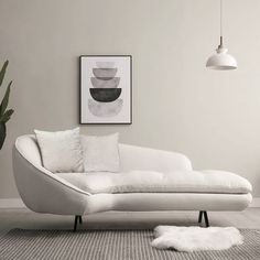 a white couch sitting next to a potted plant in a living room on top of a rug