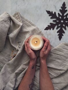 a person holding a candle on top of a table next to a snowflake