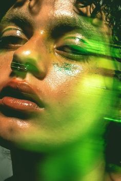 a woman's face is shown with green and yellow paint on her face, as if she was in motion