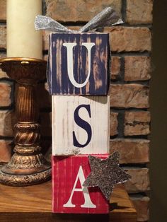 a wooden block with the letters u s and a star next to a candle