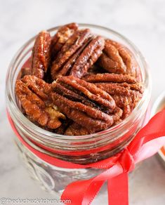 a glass jar filled with candies on top of a table next to a red ribbon