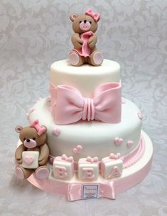 a baby shower cake with two teddy bears on top and pink ribbon around the edges